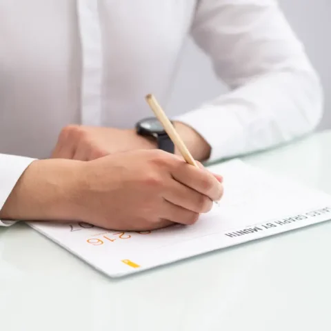 close-up-businessman-sitting-table-writing-paper