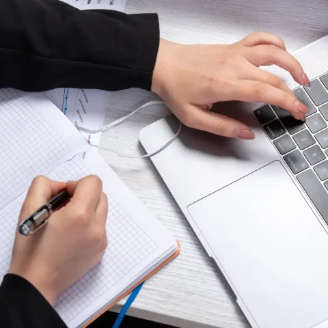 front-view-girl-taking-notes-writing-down-notes-front-table-with-schedules-graphics-using-laptop-job-business-activity