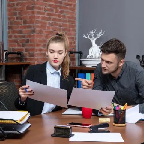 front-view-young-busy-confused-clerical-workers-discussing-one-issue-documents-office