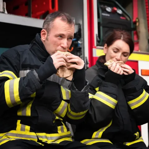 male-female-firefighters-station-having-lunch-together