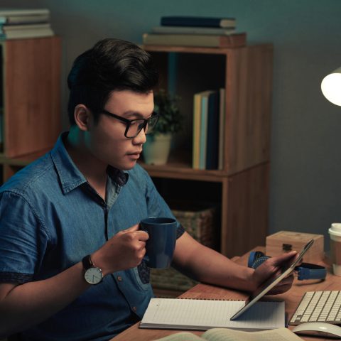 Programmer drinking coffee and reading technical specification before work