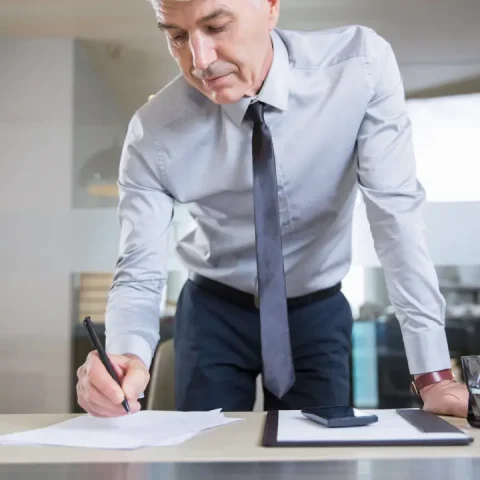 senior-businessman-bending-desk-writing