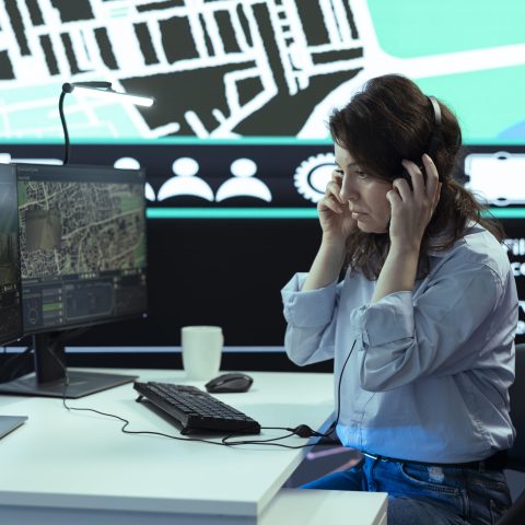 Woman operator works in call center to ensure fast order delivery to clients, handling any delay complains. Employee finding alternative routes for couriers to avoid heavy traffic via radar.